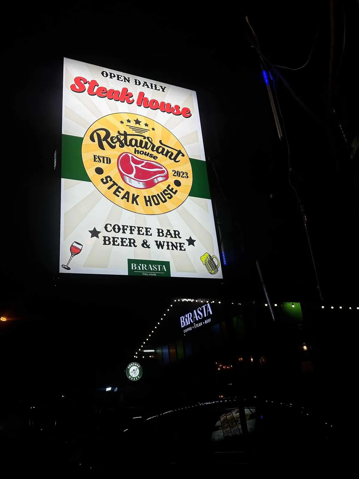 ป้ายหน้าร้านริมถนนตอนกลางคืน — สเต็กเฮาส์ บาร์กาแฟ เบียร์